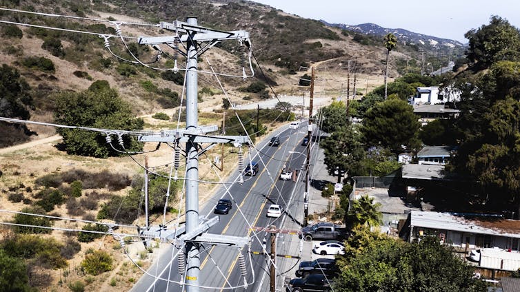Electricity poles and wires stretch above a road.